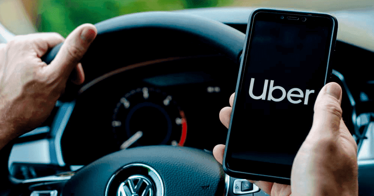 imagem de uma pessoa segurando o celular abrindo o aplicativo do uber dentro do carro.